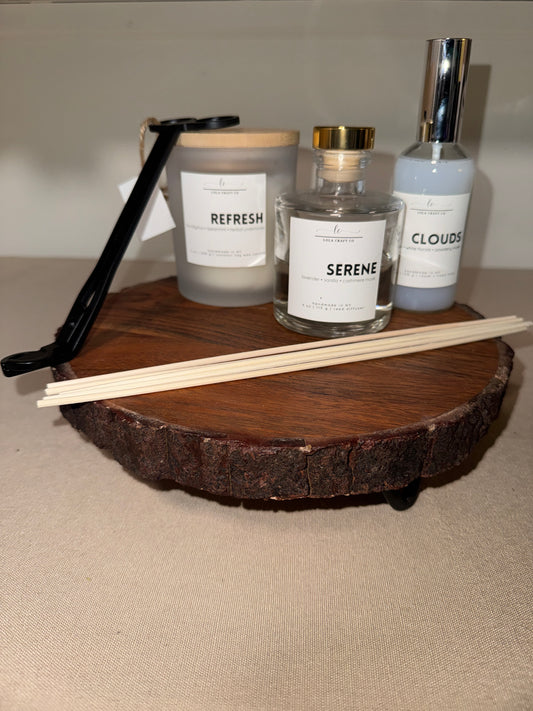 Three diffuser bottles labeled 'Clouds', 'Serene', and 'Refresh' on a wooden stand.