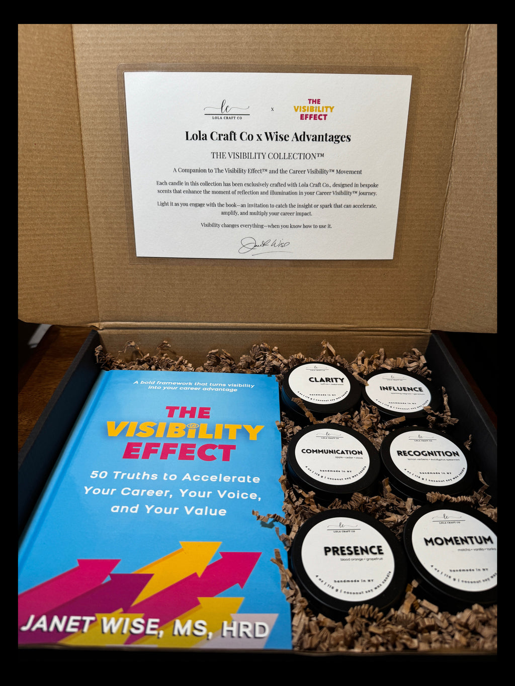 Box containing a book titled 'The Visibility Effect' by Janet Wise, a certificate, and small bottles labeled 'Momentin'.
