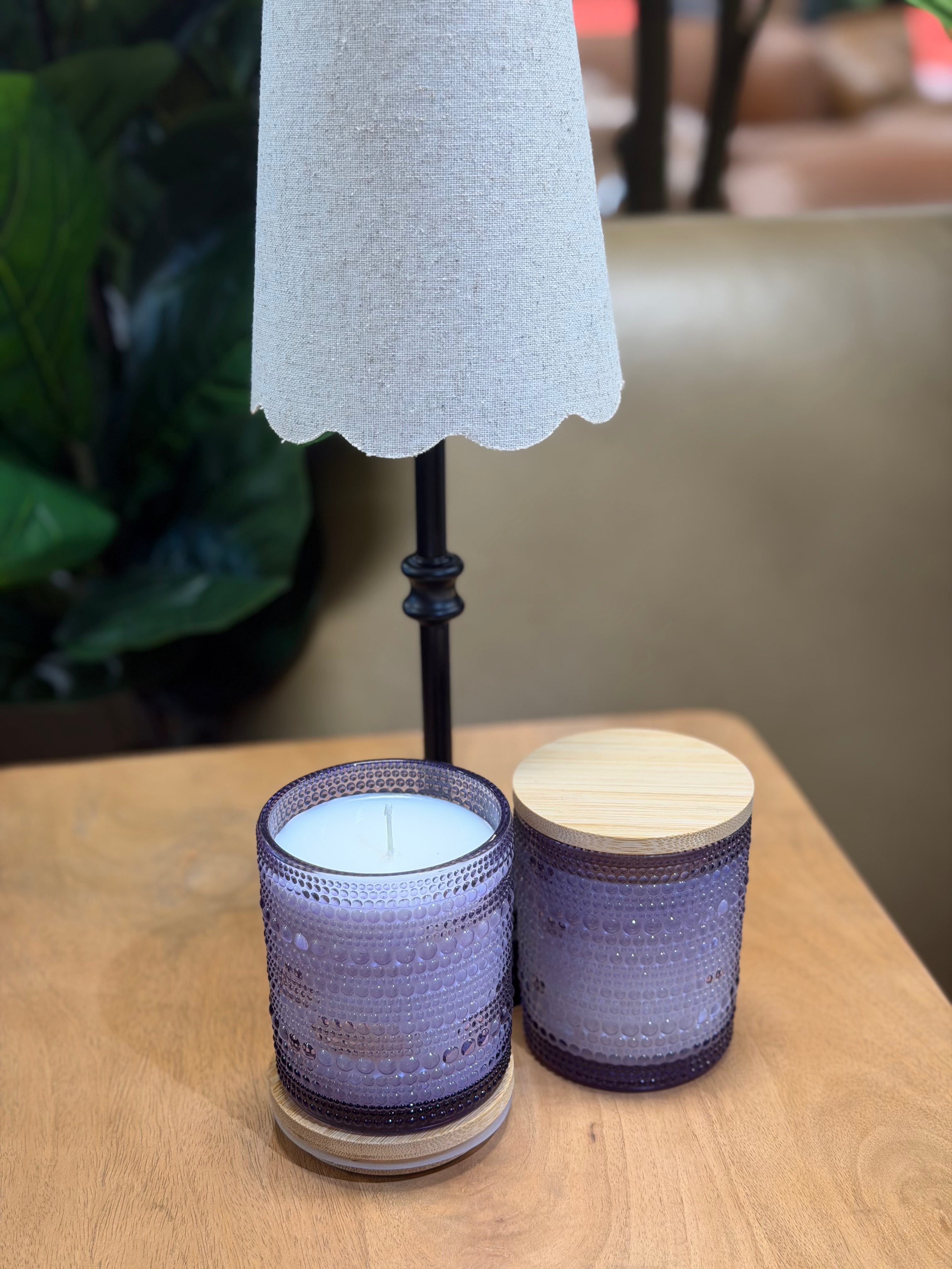 Two textured candles on a wooden surface with a blurred background
