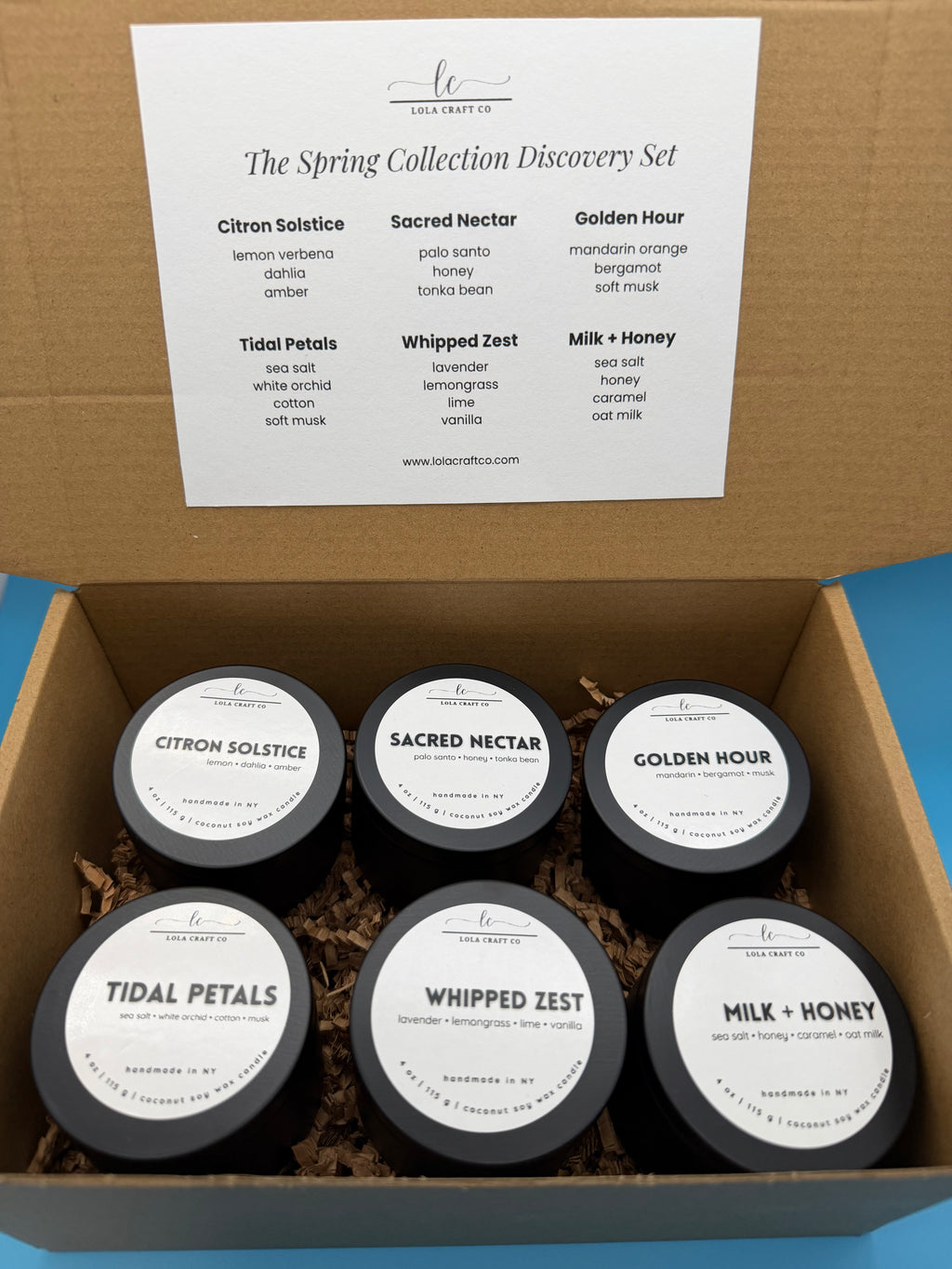 Box of six small containers with labels on a blue background