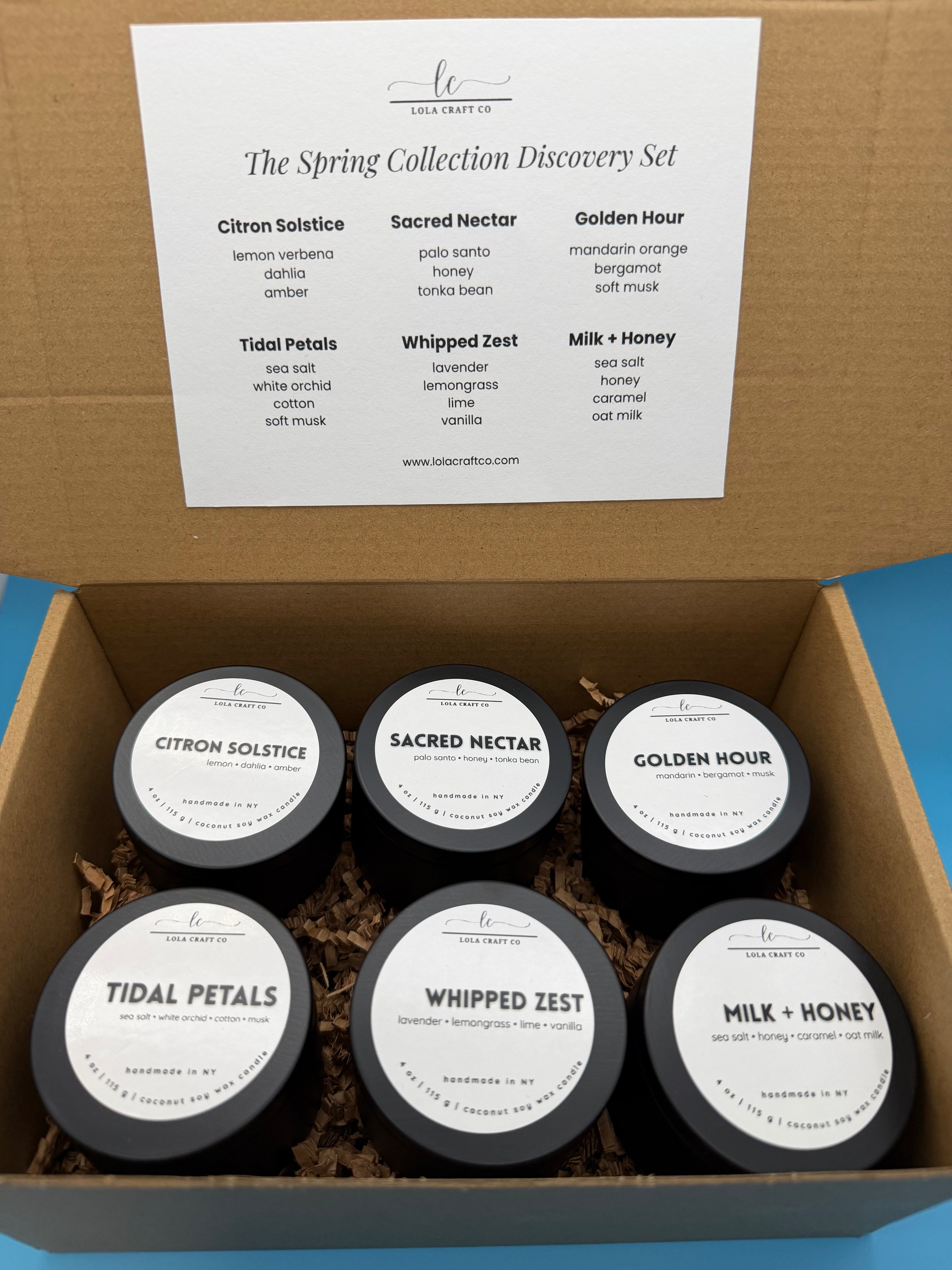 Box of six small containers with labels on a blue background