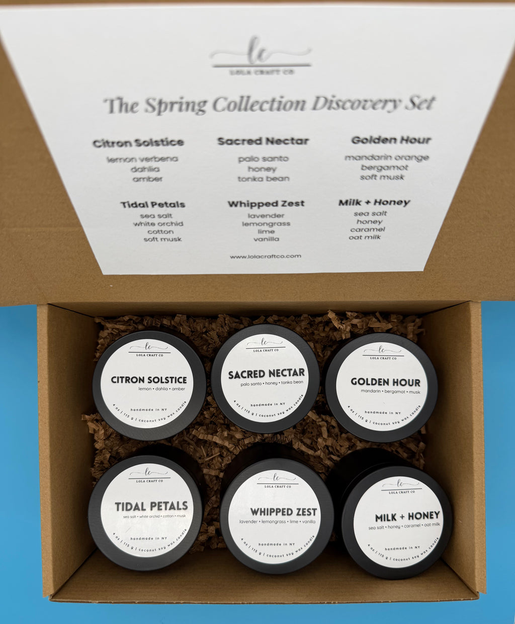 Box of 'The Spring Collection Discovery Set' with six small containers labeled 'Citron Solstice', 'Sacred Nectar', 'Golden Hour', 'Tidal Petals', 'Whipped Zest', and 'Milk + Honey'.
